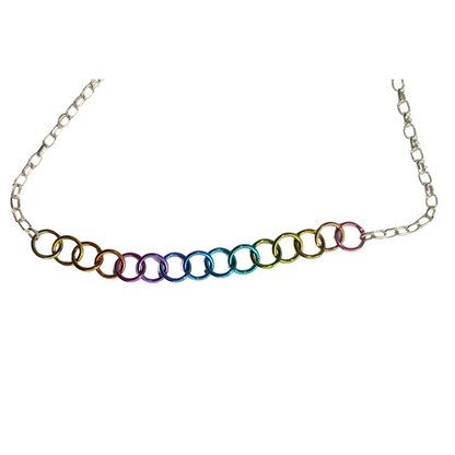 A silver-toned chain necklace featuring a row of interlocking circular links in a metallic rainbow gradient, displayed against a solid white background.